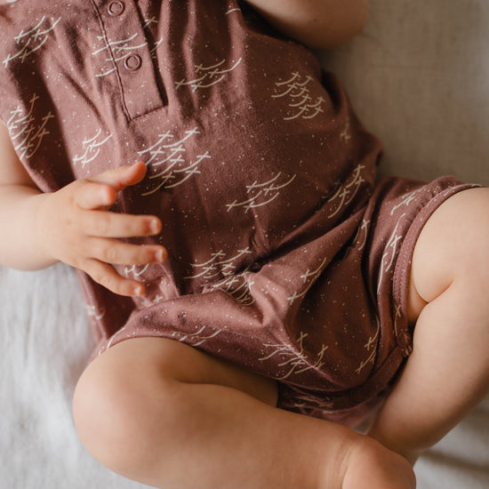 Baby wearing a patterned romper lying on a soft surface