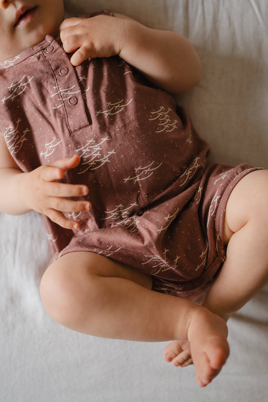 Baby wearing a patterned romper lying on a soft surface