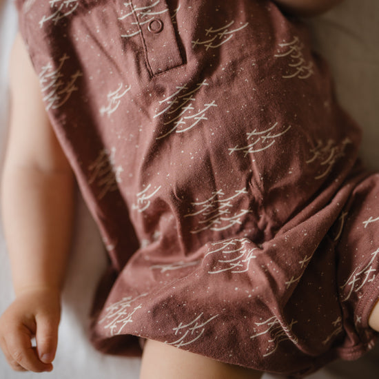 Close-up of a child wearing a patterned maroon bodysuit