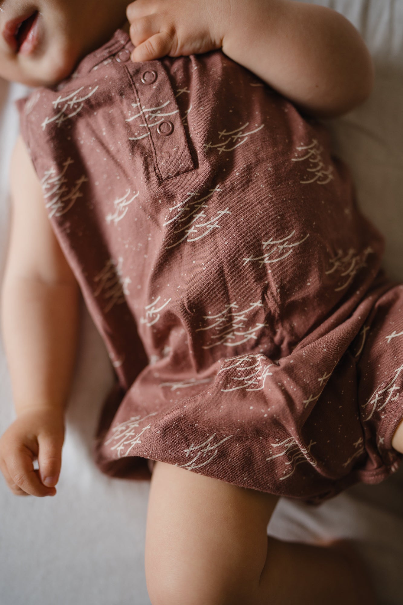 Close-up of a child wearing a patterned maroon bodysuit