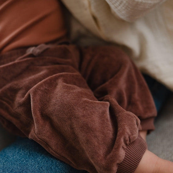 Close-up of malve pants on a child sitting on a blue jeans.