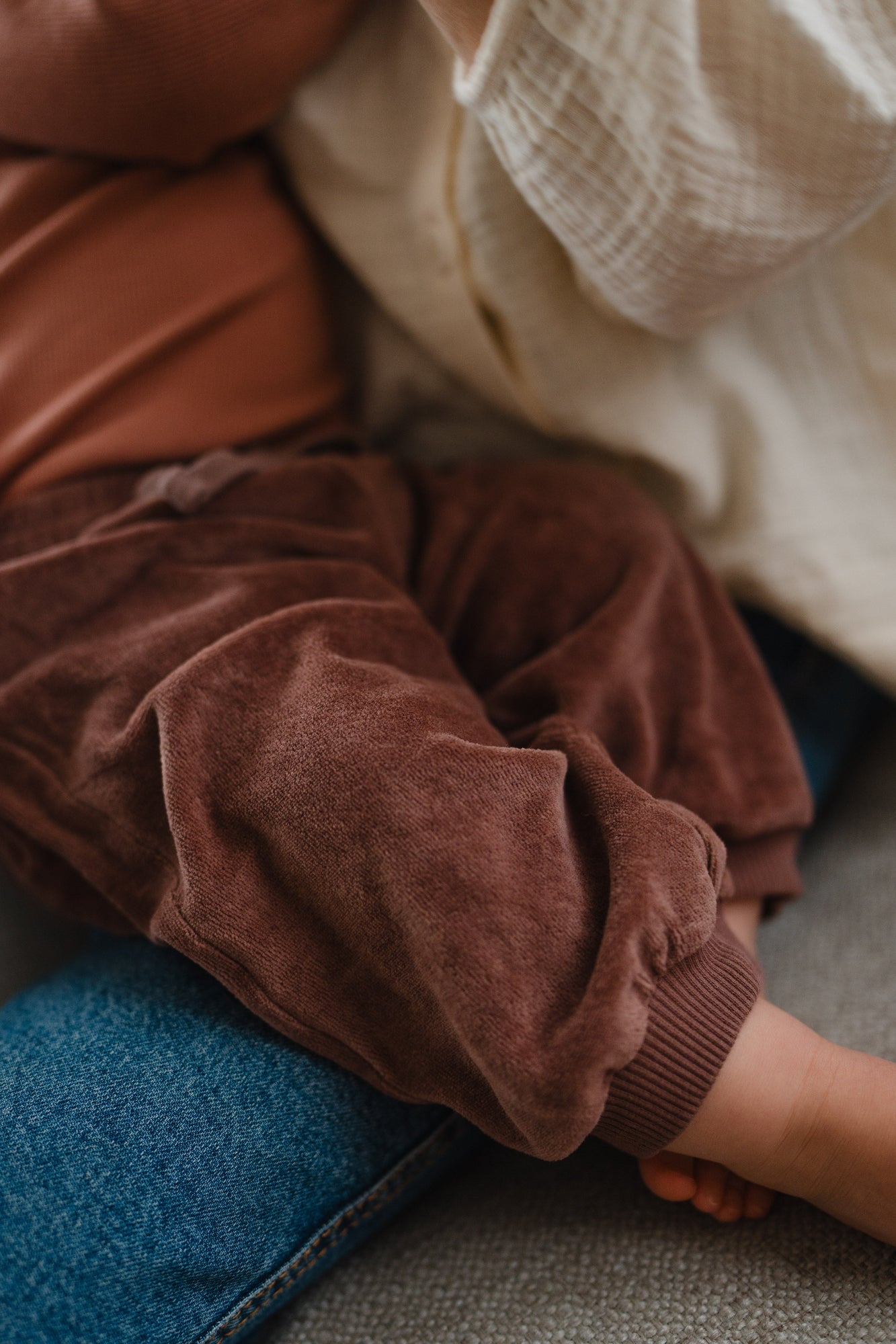 Close-up of malve pants on a child sitting on a blue jeans.